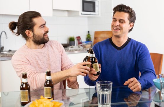 Два друга пьют дома пиво за разговором
