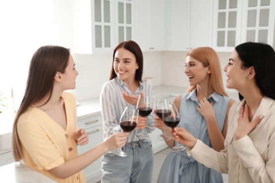 Компания девушек, распивающая вино на дружеской вечеринке