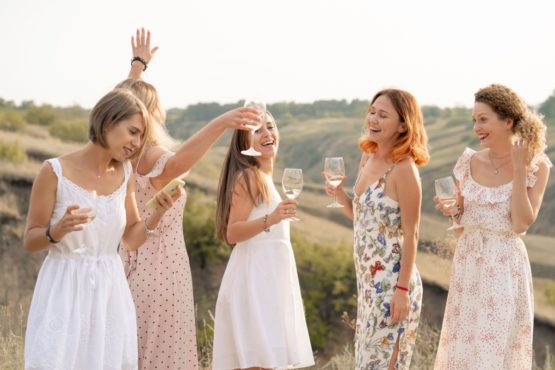Компания красивых девушек веселится на природе употребляя алкогольные напитки